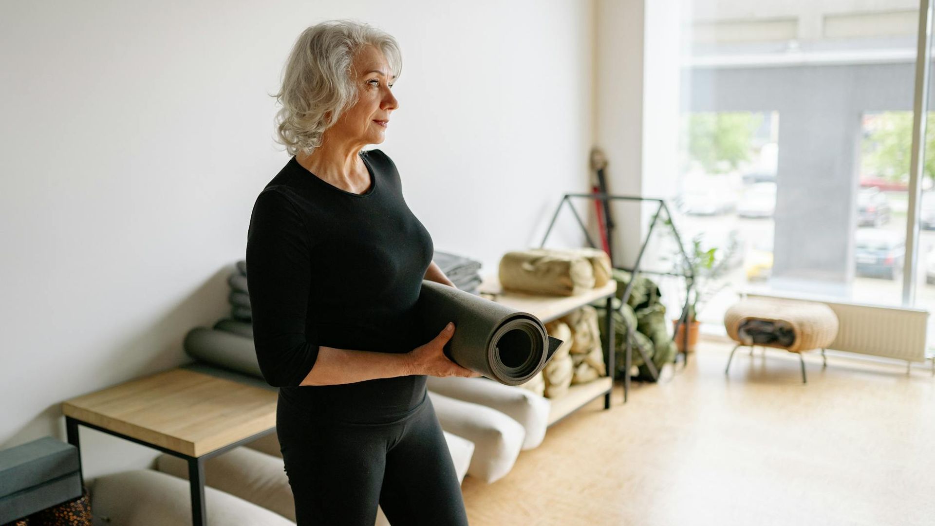 Woman in a calm yoga posture in a dark, minimalist room.